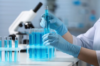 Scientist taking test tubes with samples from rack in laboratory, closeup