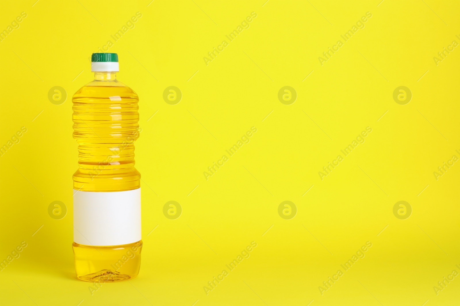 Photo of Bottle of cooking oil on yellow background. Space for text