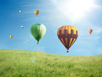 Image of Dream world. Hot air balloons in blue sky over green meadow