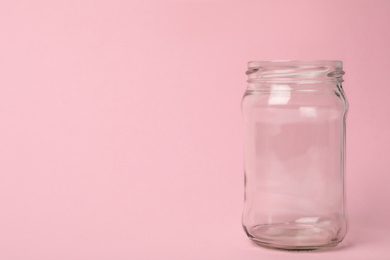 Photo of Open empty glass jar on pink background, space for text