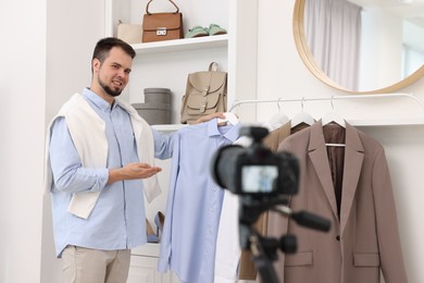 Smiling fashion blogger showing clothes while recording video at home