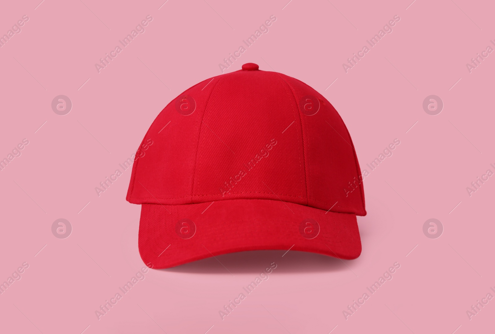 Photo of Stylish red baseball cap on pink background