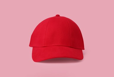 Stylish red baseball cap on pink background