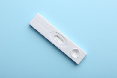 Photo of Disposable express test on light blue background, top view