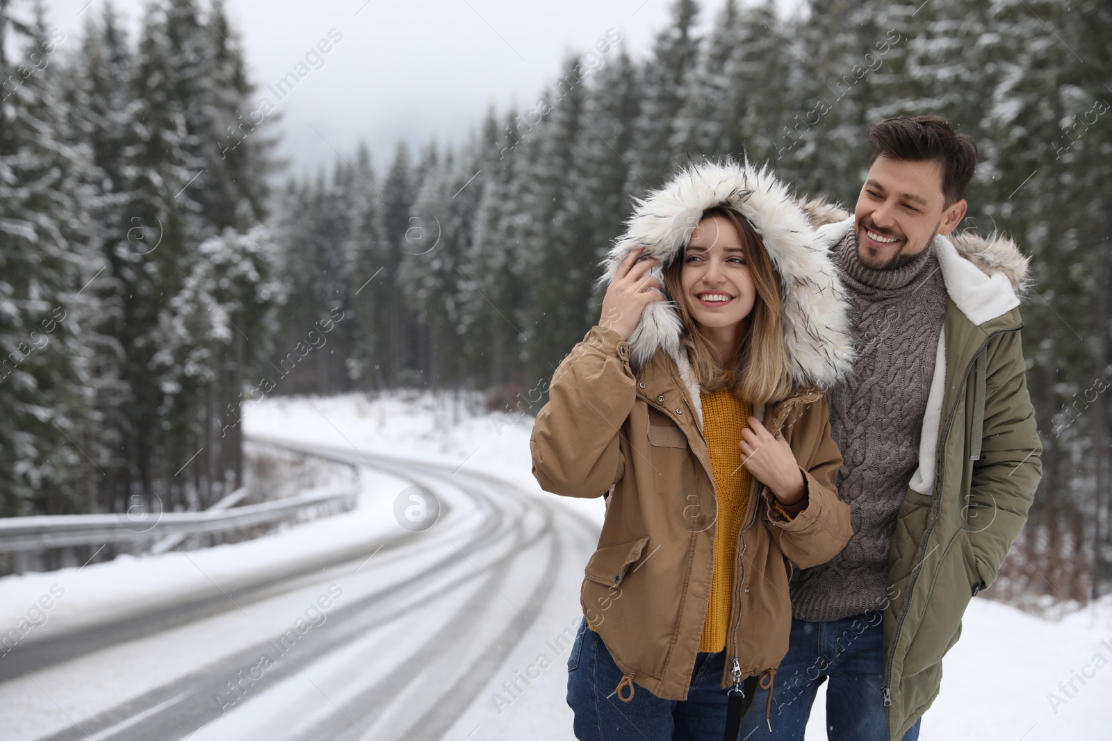 Photo of Couple walking near snowy forest, space for text. Winter vacation