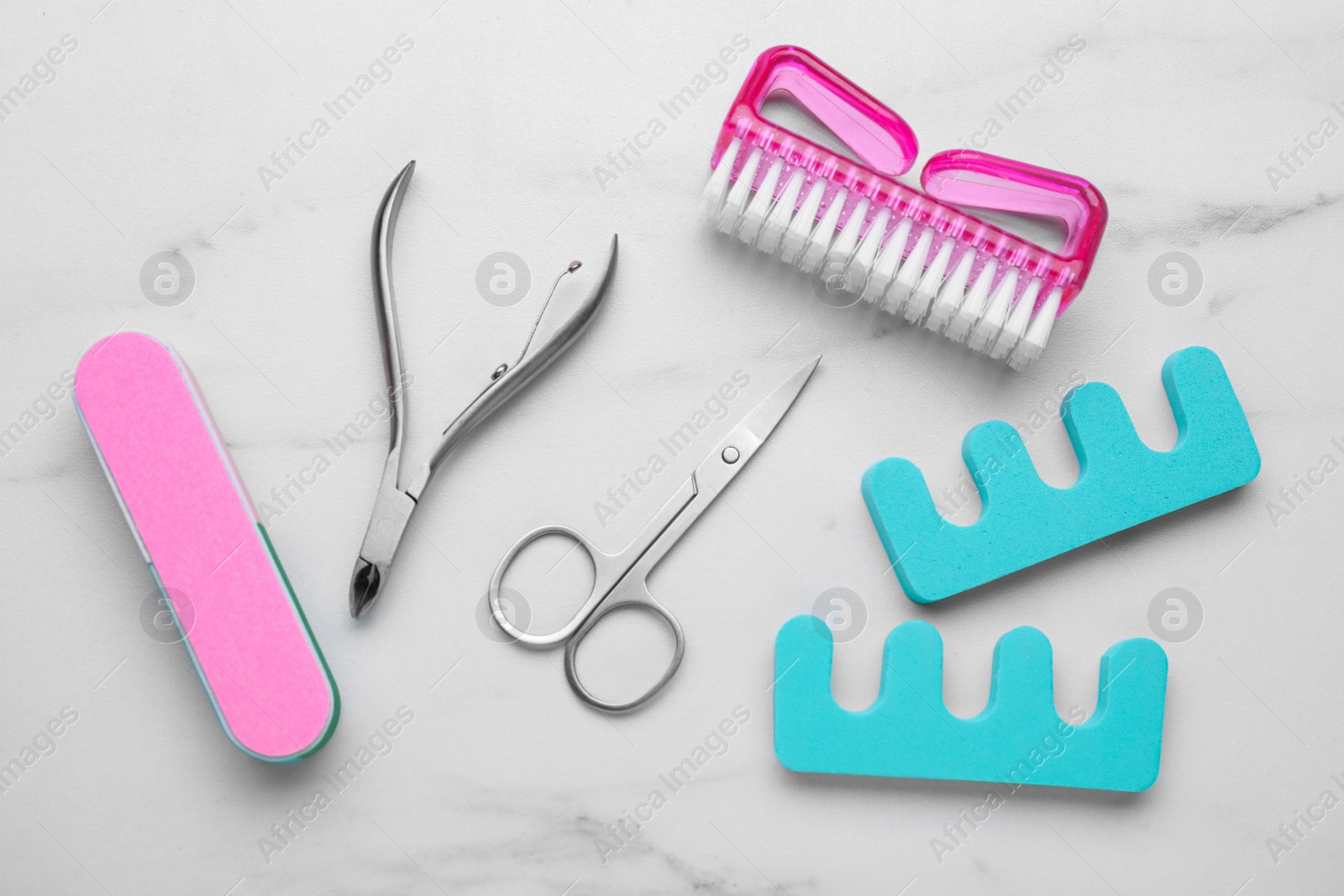 Photo of Set of pedicure tools on white marble table, flat lay