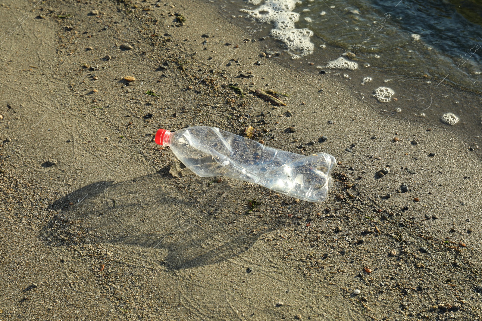 Photo of Used plastic bottle near water at beach. Environment pollution