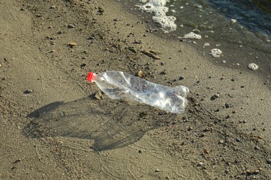 Used plastic bottle near water at beach. Environment pollution