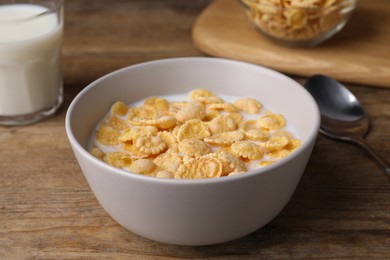 Photo of Tasty cornflakes with milk in bowl on wooden table