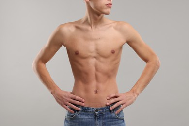 Shirtless man with slim body on grey background, closeup