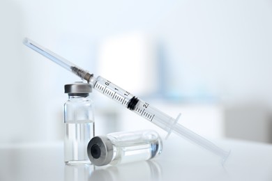 Photo of Syringe with vials of medicine on white table