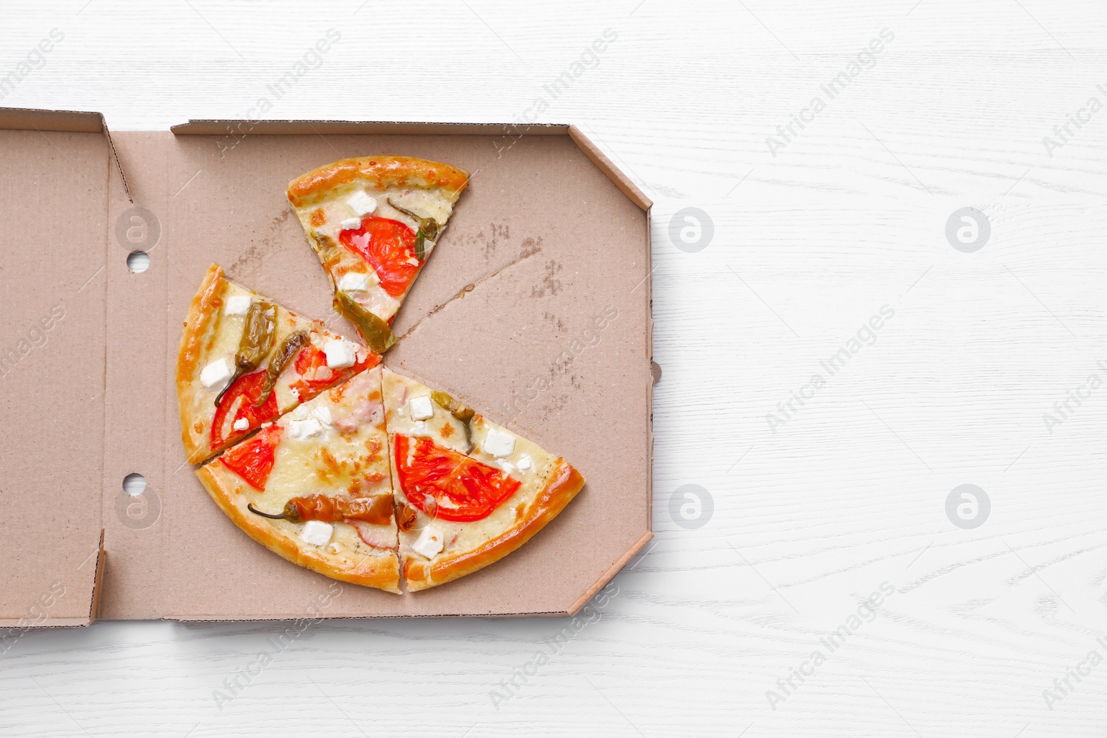 Photo of Cardboard box with tasty pizza slices on wooden background, top view with space for text