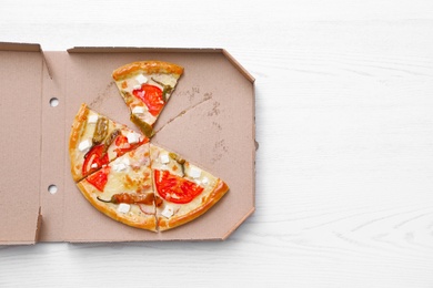 Cardboard box with tasty pizza slices on wooden background, top view with space for text