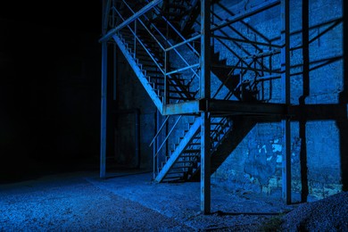 Old building with fire escape at night, toned in blue