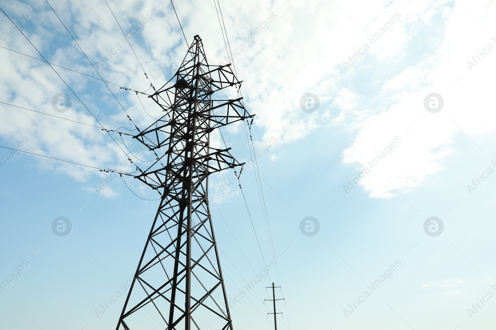 Photo of Telephone poles and wires against blue sky with clouds