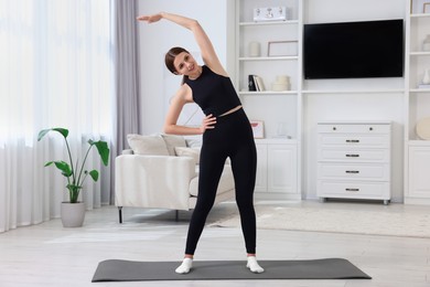 Photo of Morning routine. Happy woman doing stretching exercise at home