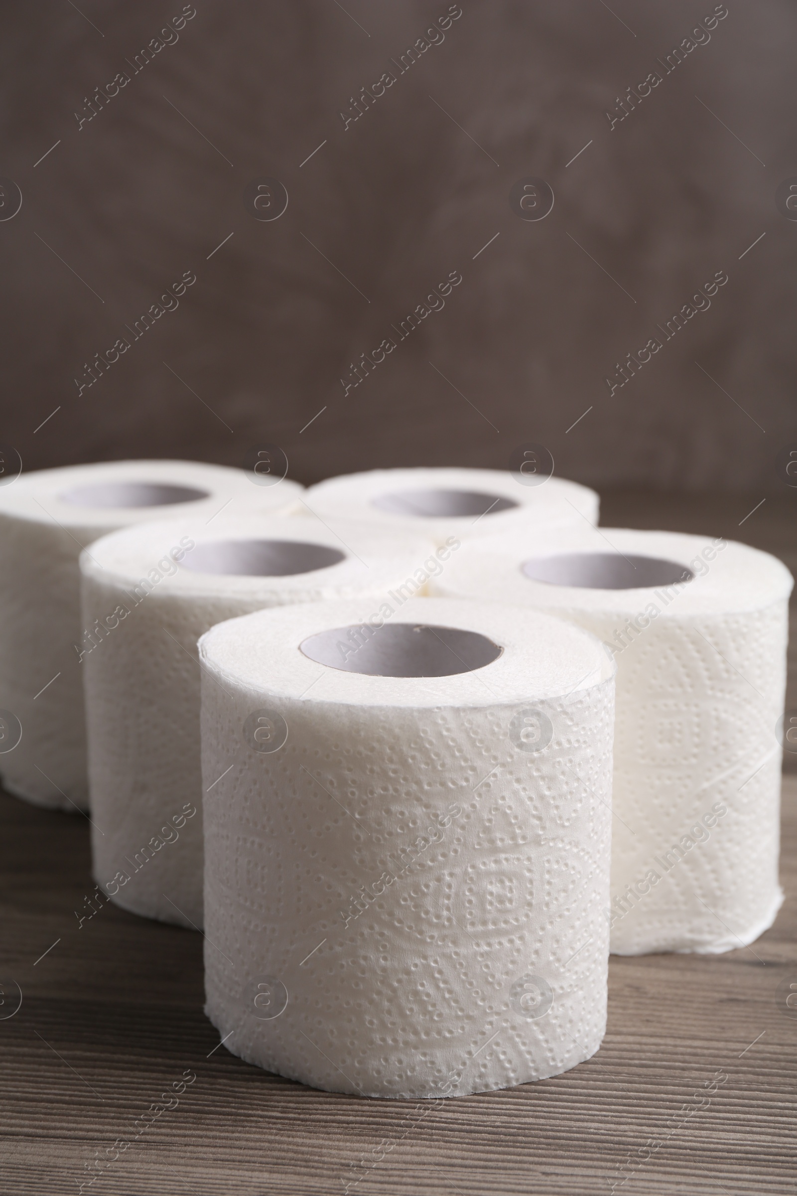 Photo of Soft toilet paper rolls on wooden table, closeup