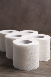 Photo of Soft toilet paper rolls on wooden table, closeup