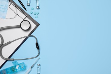 Flat lay composition with medical objects on light blue background, space for text