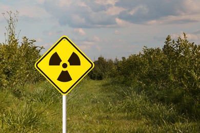 Image of Radioactive pollution. Yellow warning sign with hazard symbol in rural area