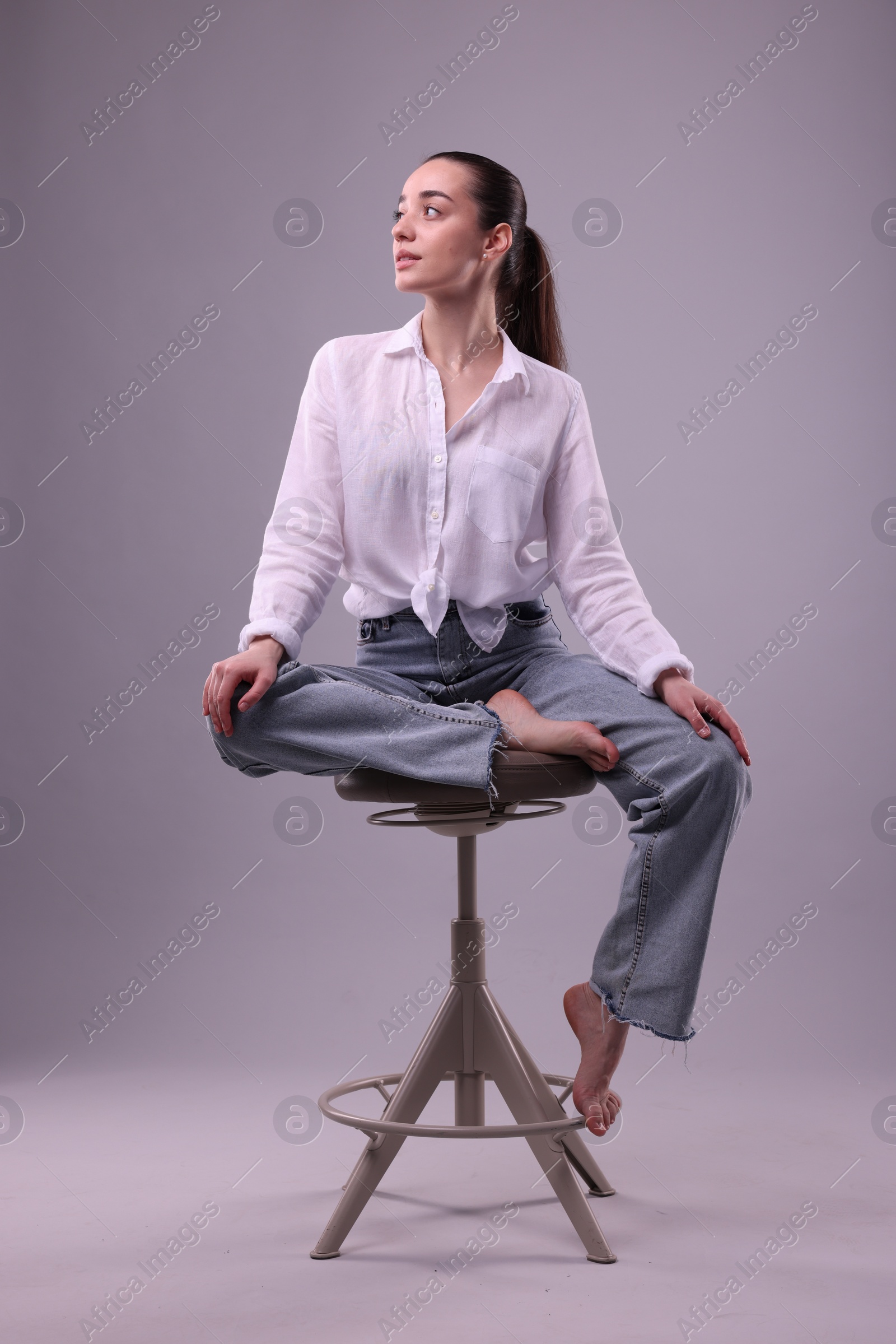 Photo of Portrait of beautiful young woman sitting on chair against light grey background