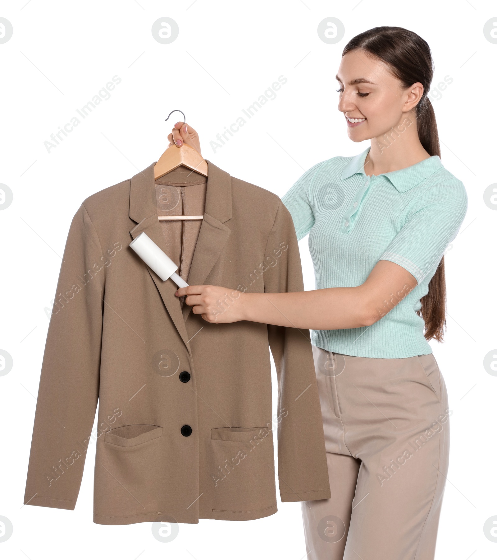 Photo of Young woman cleaning suit with lint roller on white background