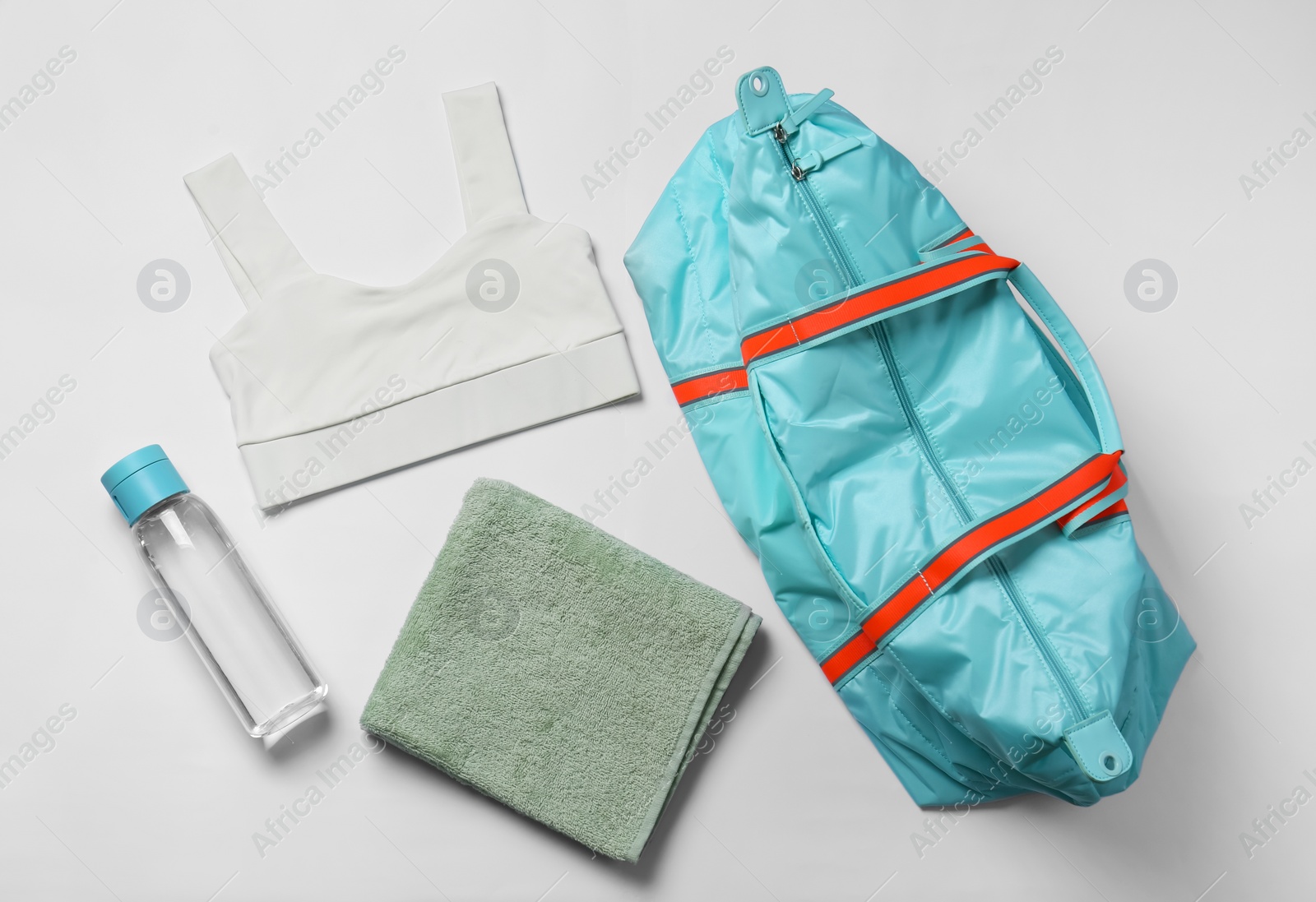 Photo of Gym bag, yoga sportswear, towel and bottle of water on white background, flat lay