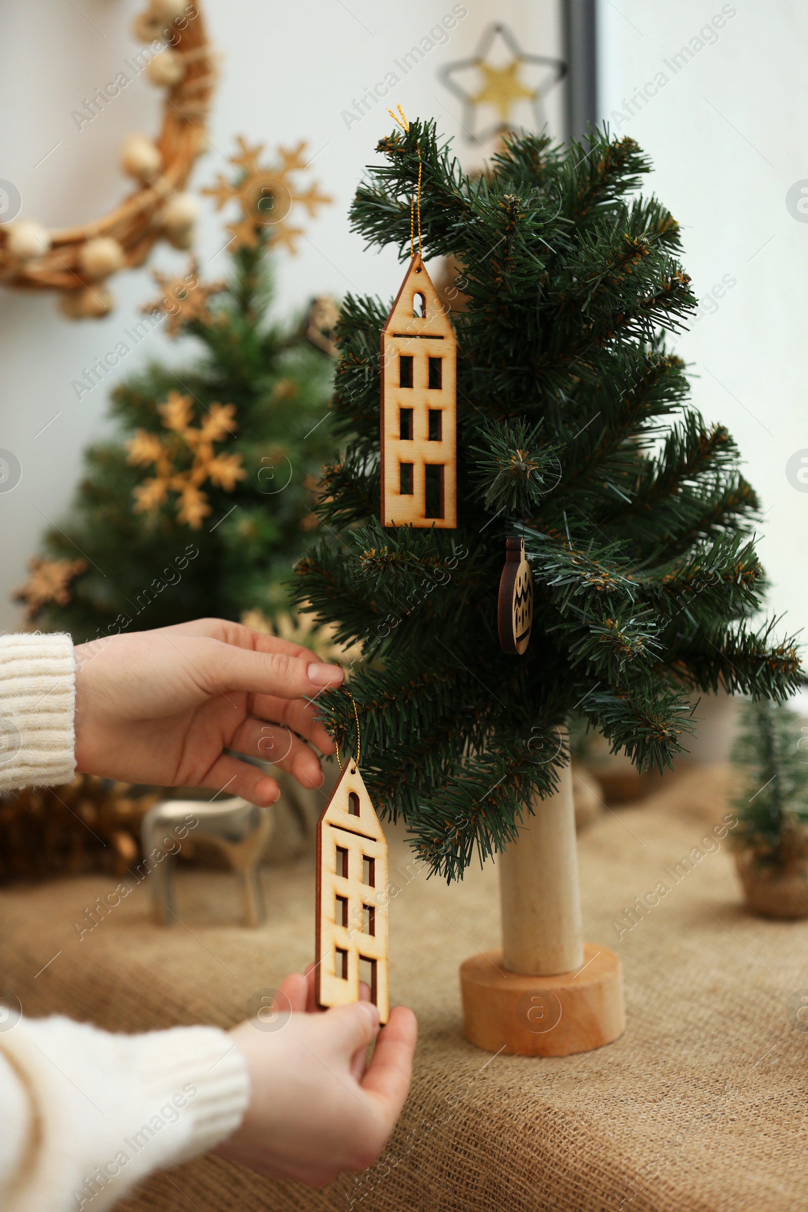 Photo of Woman decorating small Christmas tree on window sill indoors, closeup