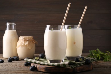 Tasty yogurt in glasses and blueberries on wooden table, closeup