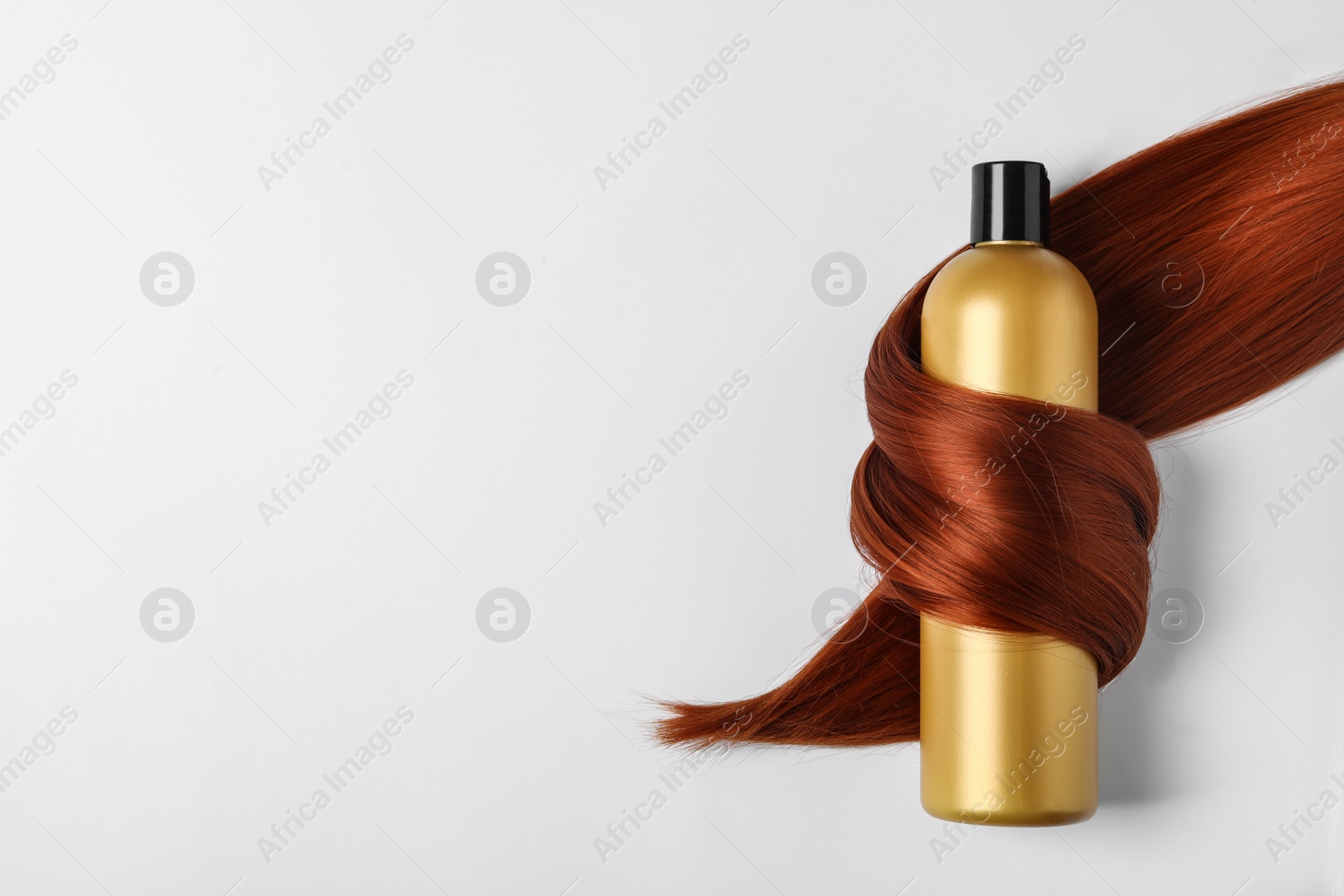 Photo of Shampoo bottle wrapped in lock of hair isolated on white, top view. Natural cosmetic products