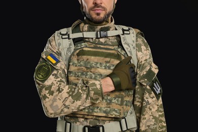 Soldier in Ukrainian military uniform on black background, closeup