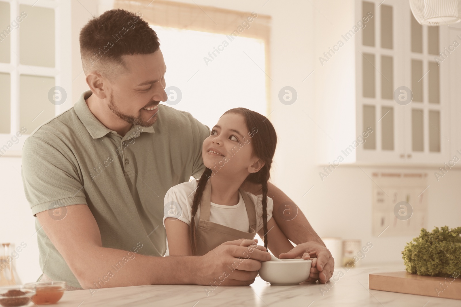 Photo of Father and daughter with mortar in kitchen. Cooking together