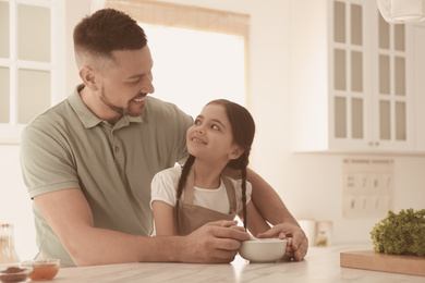 Father and daughter with mortar in kitchen. Cooking together