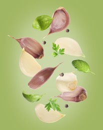 Image of Fresh garlic cloves, basil, peppercorns and parsley falling on green background