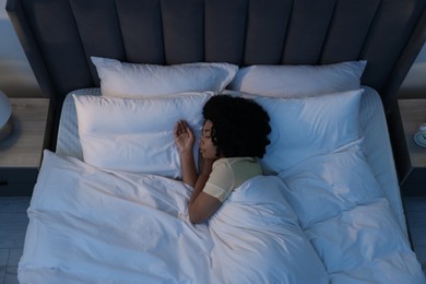 Photo of Young woman sleeping in soft bed at night, above view