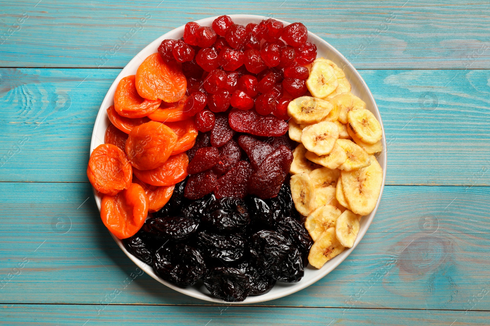 Photo of Delicious dried fruits on light blue wooden table, top view