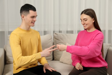 Happy people playing rock, paper and scissors in room