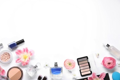 Flat lay composition with different makeup products and beautiful spring flowers on white background, space for text