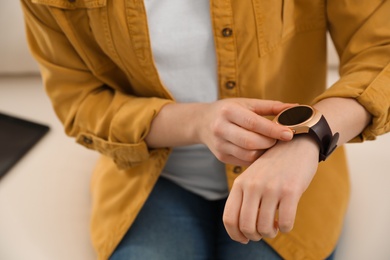 Woman checking smart watch at home, closeup