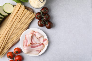 Photo of Raw pasta and fresh ingredients on light grey table, flat lay. Space for text