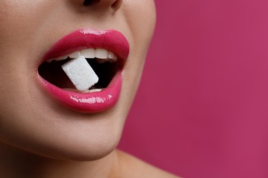 Photo of Woman with beautiful lips eating sugar cube on pink background, closeup. Space for text