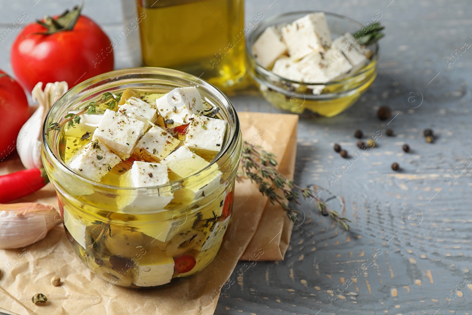 Photo of Composition with pickled feta cheese in jar on grey wooden table, space for text