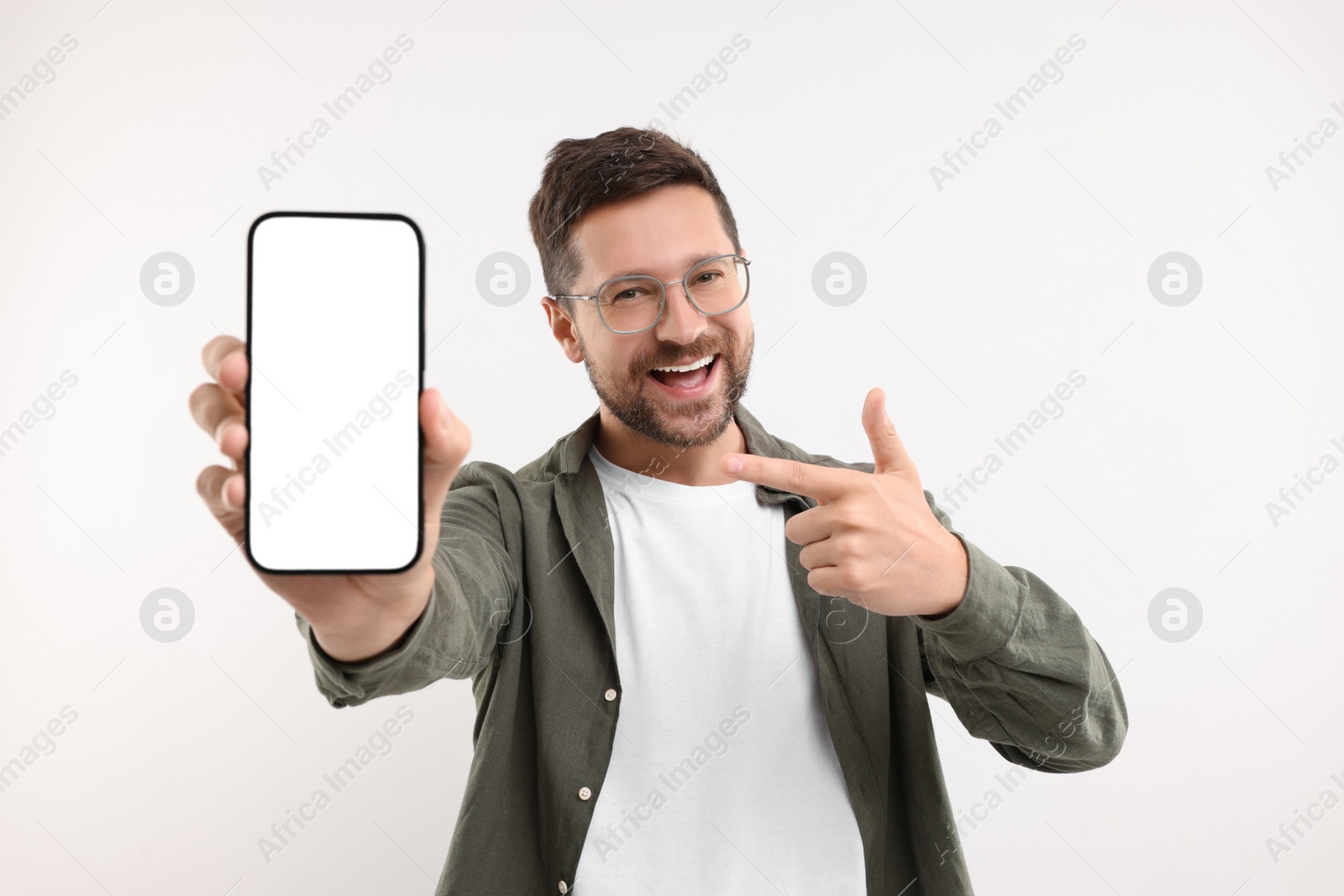 Photo of Handsome man showing smartphone in hand and pointing at it on white background