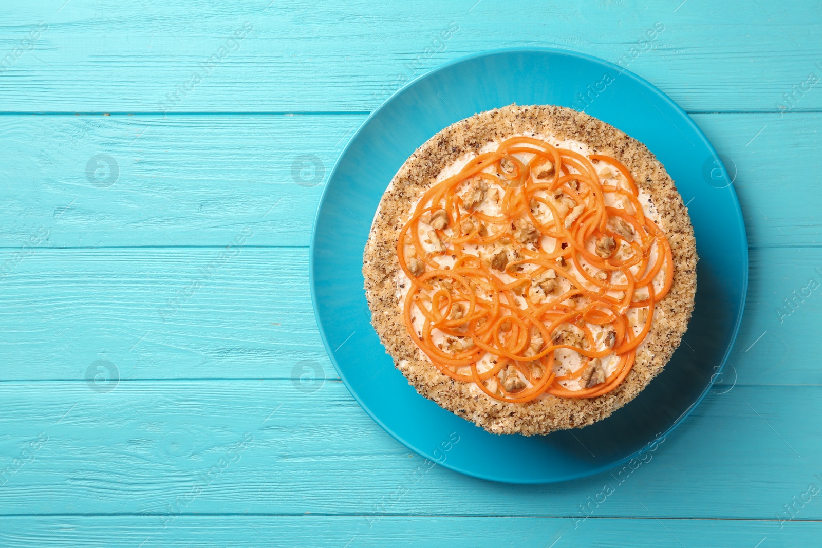 Photo of Dish with delicious carrot cake on blue wooden background, top view. Space for text