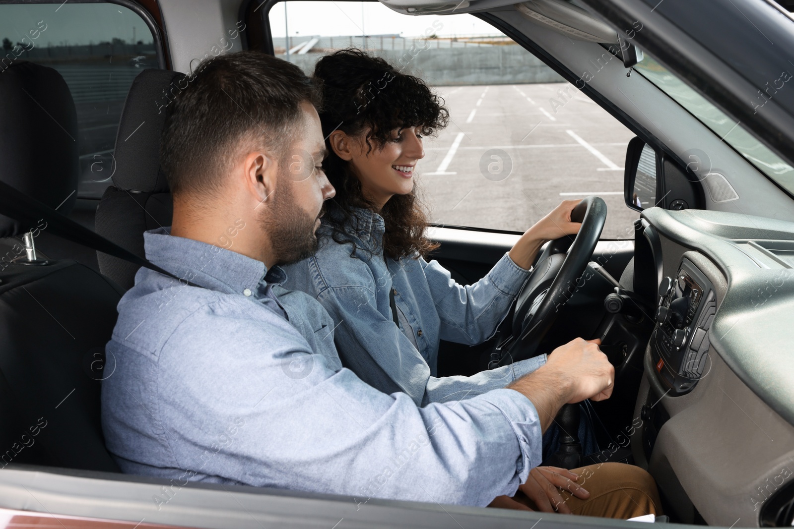 Photo of Driving school. Happy student during lesson with driving instructor in car at parking lot