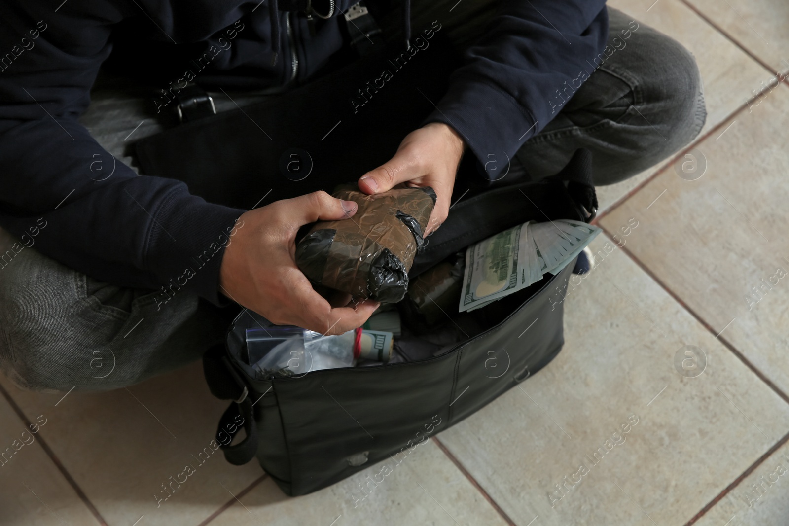 Photo of Drug dealer with narcotics and money sitting on floor, closeup view