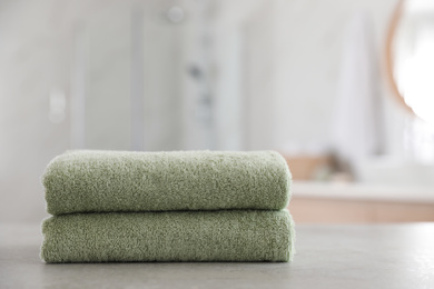 Stack of clean towels on table in bathroom