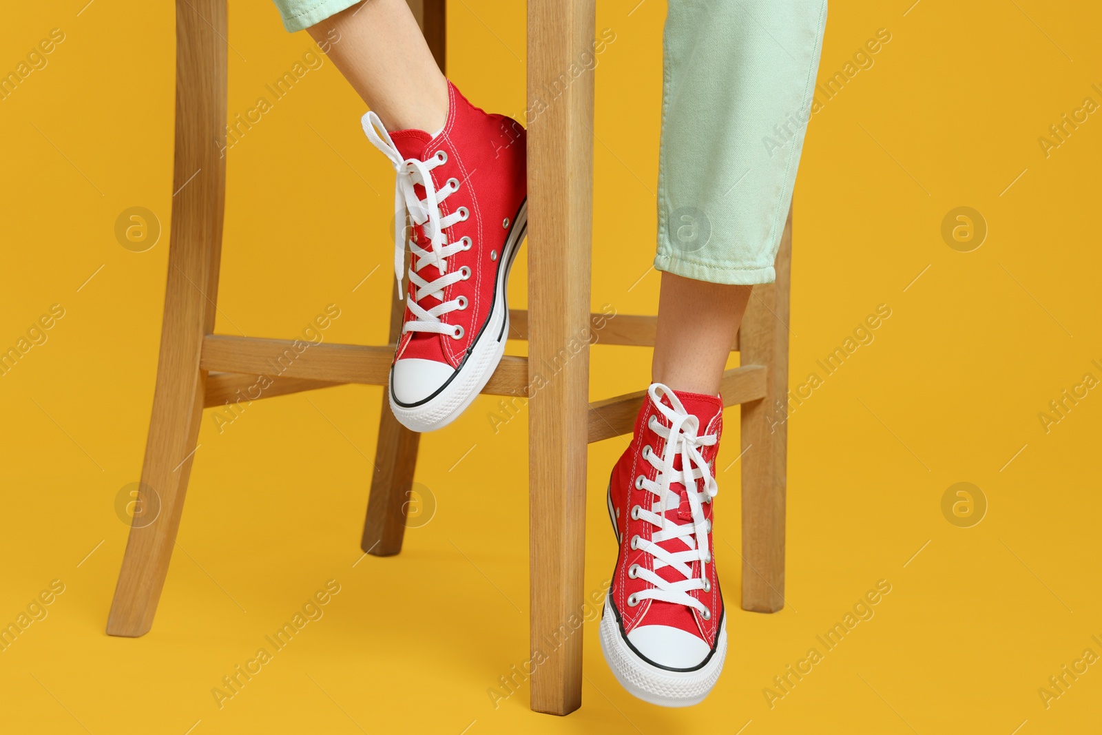 Photo of Woman in stylish gumshoes on yellow background, closeup