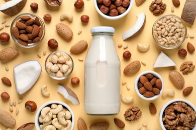 Photo of Vegan milk and different nuts on beige background, flat lay