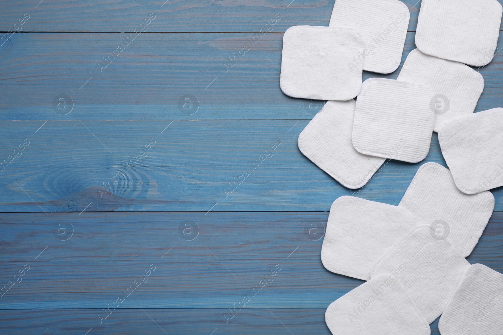 Photo of Many clean cotton pads on light blue wooden table, flat lay. Space for text